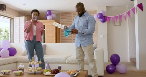 African American Couple Pouring Drinks at Lavender-Themed Living Room Party