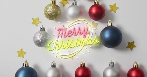Glowing neon merry christmas script with baubles, glitter stars and clear beads flatlay