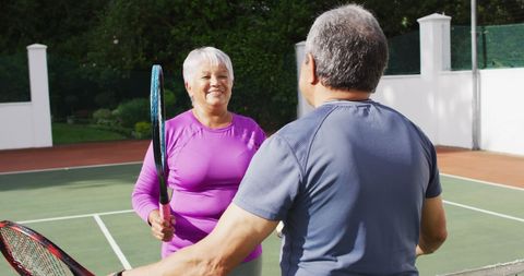 Senior couple celebrating tennis match on outdoor court