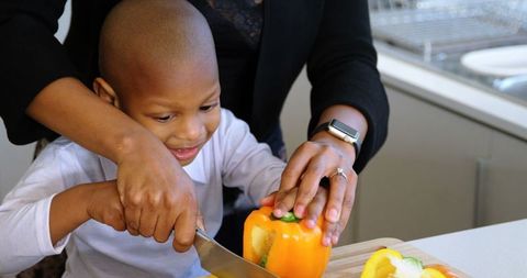 Mother Teaching Son to Cut Vegetables in Kitchen