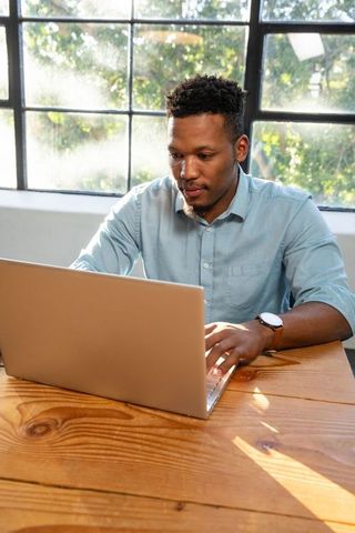 Focused man working on laptop in bright workspace