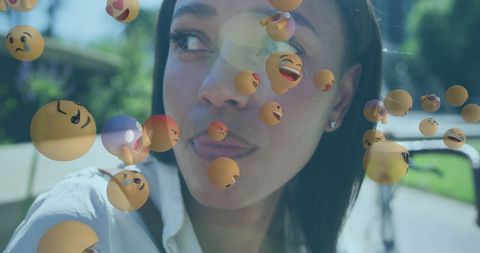 Smiling Woman Surrounded by Floating Emojis Outdoors