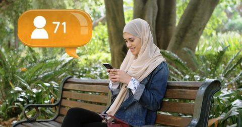 Muslim Woman Enjoying Social Media on Park Bench