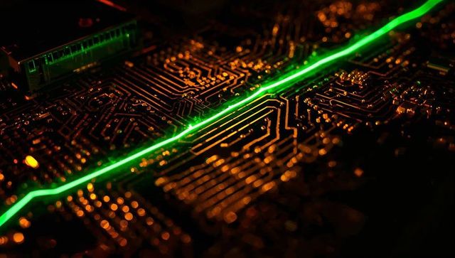 Green laser cutting across copper pcb traces with amber glow macro electronics