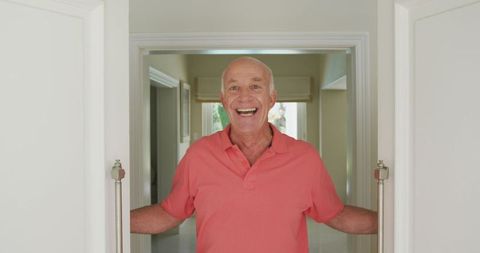 Cheerful senior man opening doorway in home