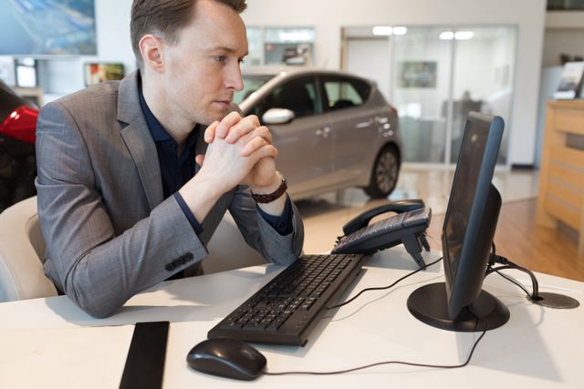 Salesman using computer while working in car showroom - Download Free Stock Photos Pikwizard.com