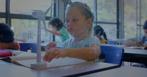 Young student interacting with miniature wind turbine in classroom STEM learning moment