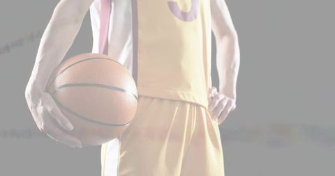 Female basketball player holding ball at hip in yellow jersey closeup athletic focus
