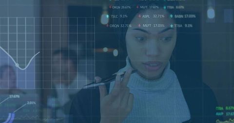 Young professional analyzing transparent financial dashboard on glass display in corporate office