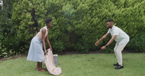 Young Couple Preparing Picnic Blanket on Lawn