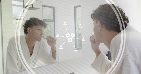 Young man brushing teeth in mirror wearing bathrobe holding teal toothbrush daily routine