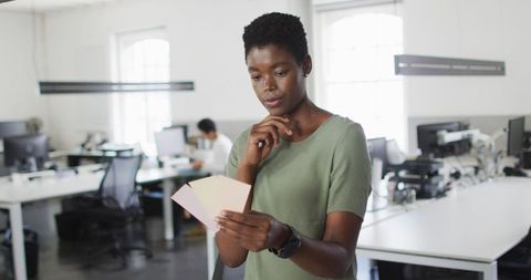 Focused african american businesswoman evaluating color swatches in modern office