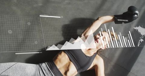 Female athlete recovering on gym mat with boxing glove and real-time fitness data hud