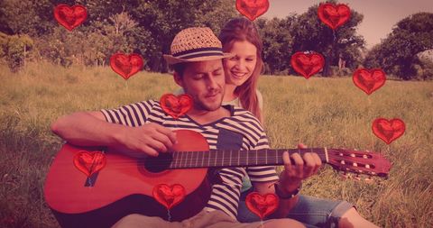 Romantic Couple in Field with Guitar and Floating Hearts