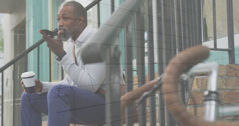 Older Man with Smartphone Sitting on Steps Relaxing with Coffee