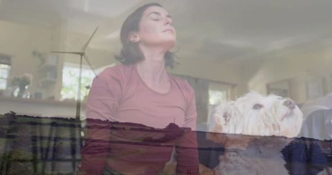 Woman meditating with dog double exposure wind turbine countryside calm