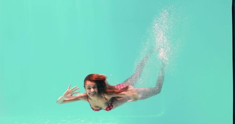 Underwater Serenity: Woman in Red Bikini Waving in Clear Pool