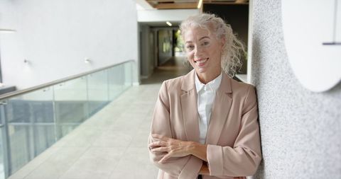 Smiling Businesswoman with Silver Hair in Modern Office Hallway