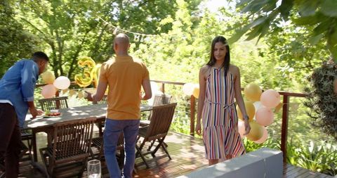 Diverse Friends Setting Up Outdoor Birthday Party in Sunny Garden