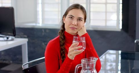 Businesswoman Pondering While Drinking Water at Office Desk