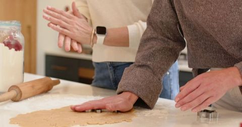 Mother and adult daughter pressing cookie cutter into dough while baking together
