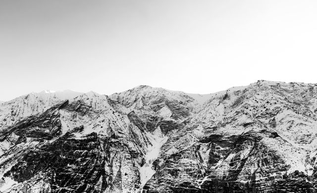Snow-covered mountains depicted in black and white create a dramatic and timeless feel. Ideal for nature and adventure-themed projects, motivational posters, backgrounds and winter holiday promotions.