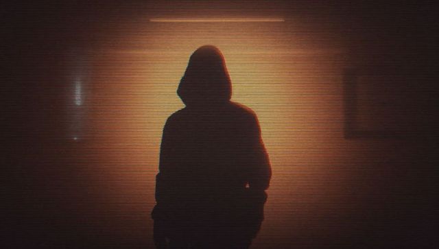 Mysterious Hooded Figure in Dimly Lit Hallway