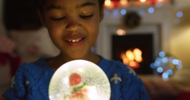 Child in Blue Sweater Holding Snow Globe in Cozy Living Room - Download Free Stock Images Pikwizard.com