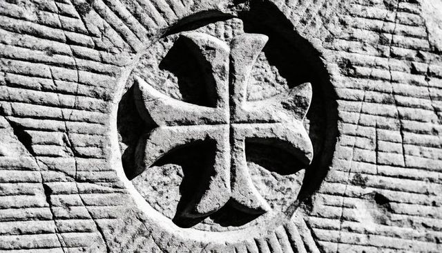 Revealing recessed stone medallion featuring four-armed flared cross and chisel grooves