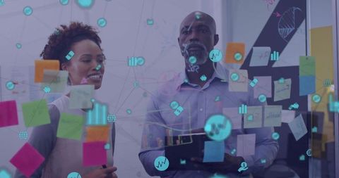 Diverse team collaborating at glass board with sticky notes and AR data visualizations