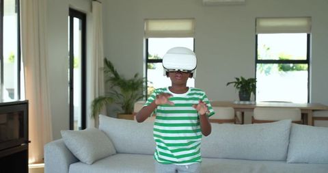 African American Boy Experiencing Virtual Reality in Bright Modern Living Room Wearing VR Headset