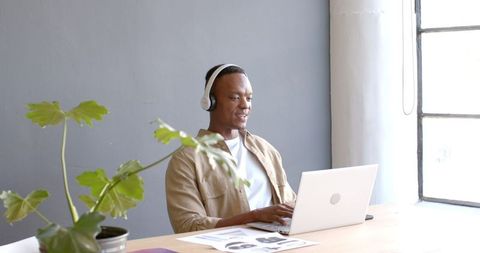 Smiling Professional Wearing Headphones Using Laptop for Video Conference