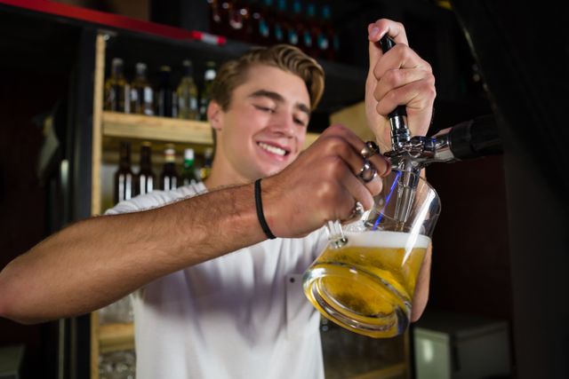 Young bartender pouring draft beer into a glass at a bar counter. Ideal for use in advertisements for bars, pubs, and nightlife venues, as well as promotional materials for hospitality services and beer brands.