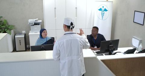 Multicultural medical team consulting at modern clinic reception with clinician in lab coat