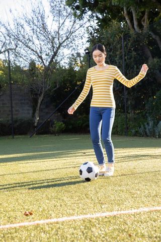 Woman Dribbling Soccer Ball on Sunny Field