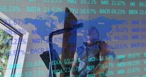 Exercising fit man on elliptical with translucent global stock market overlay at home gym