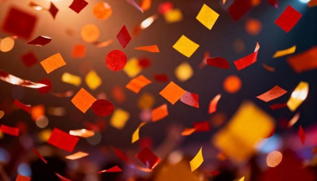 Drifting red and orange confetti over concert crowd with bokeh lights and spotlights