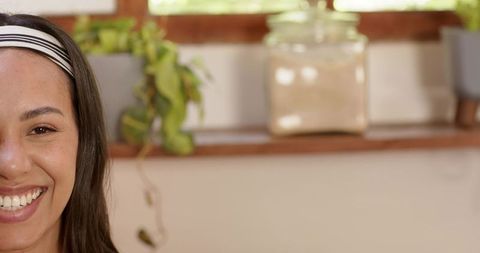 Woman Smiling at Sunny Windowsill with Plants and Glass Jar
