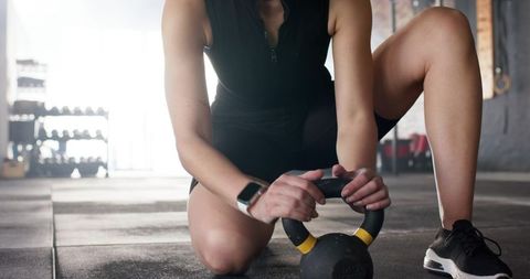 Female athlete gripping kettlebell for gym workout