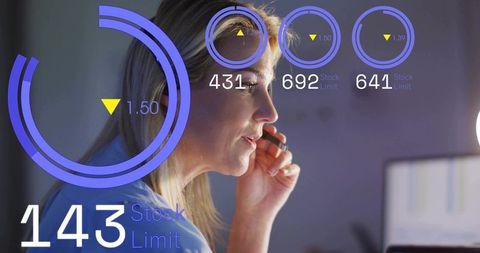 Mature woman monitoring hud analytics while holding headset at modern workstation