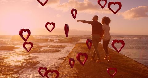 Romantic Couple Walking by Beach at Sunset with Red Hearts Overlay