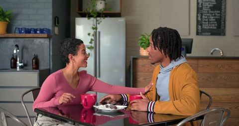 Couple sharing warm coffee conversation in cozy modern cafe kitchenette, intimate moment