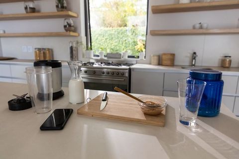Preparing morning smoothie with peanut butter on cutting board in modern bright kitchen