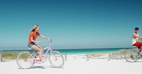 Joyful Couple Cycling on Seaside Path in Summer