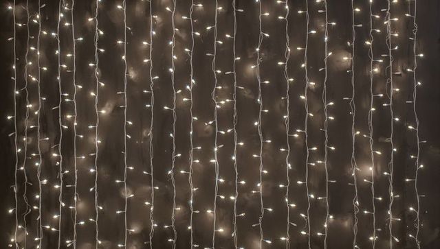 Hanging Warm White LED Curtain Lights Glowing on Dark Wall for Festive Ambient Texture