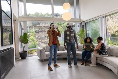 Friends enjoying virtual reality and tablet entertainment in bright modern living room