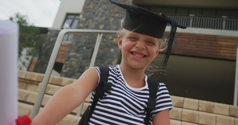Joyful Schoolgirl Celebrates Graduation with Diploma and Cap