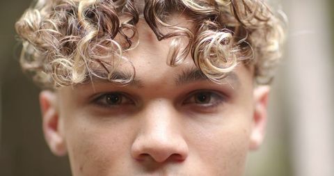 Close-up portrait of young man with highlighted curls