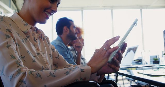 Woman Smiling and Using Tablet in Modern Office with Colleagues - Download Free Stock Images Pikwizard.com