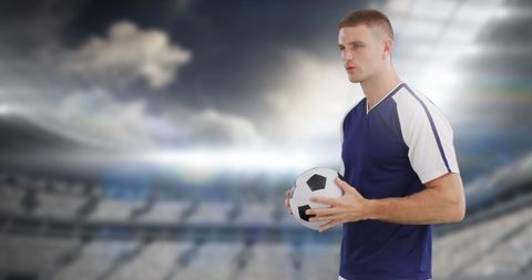 Focused Soccer Player Holding Ball in Sunlit Stadium